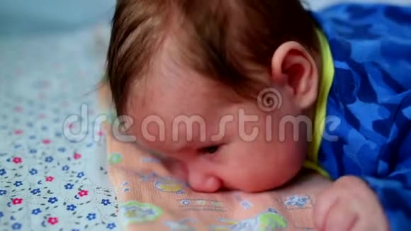 婴儿躺在他的肚子上大眼睛在床上为新生儿打开视频的预览图