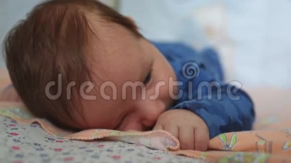 婴儿躺在他的肚子上大眼睛在床上为新生儿打开视频的预览图