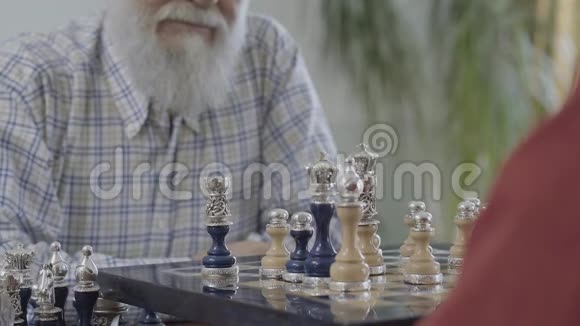 无法辨认的人的手放下了一颗棋子两个人在棋盘上握手美丽的棋盘视频的预览图