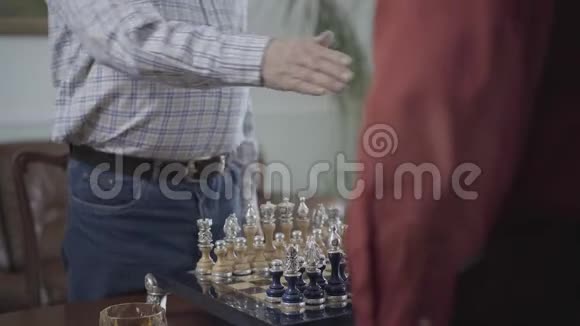 两个人在开始比赛前在棋盘上握手坐在小桌旁美丽的国际象棋视频的预览图
