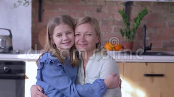 爱的母亲幸福的母亲的肖像小女儿拥抱和亲吻脸颊在厨房在家视频的预览图