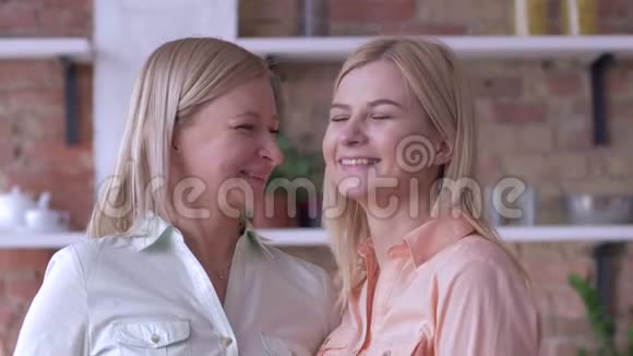 妈妈亲吻美丽的家庭妈妈和成年女儿的肖像微笑着看着镜头特写视频的预览图