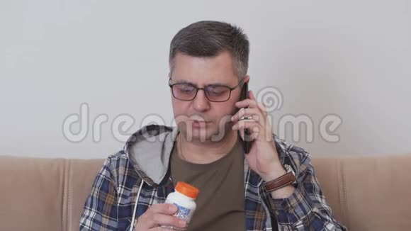 一个中年男人坐在沙发上手里握着一只手看着一罐药丸在他身上说话视频的预览图