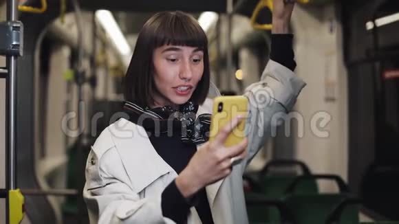 年轻的微笑女子在乘坐公共交通工具时有一个视频电话城市灯光背景视频的预览图