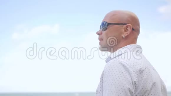 站在海滩上的秃头人的侧视他在看海近距离射击视频的预览图