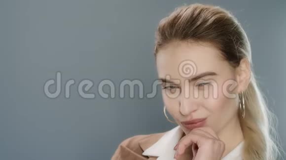 性感女人在灰色摄影棚背景下对镜头摆姿势和眨眼视频的预览图