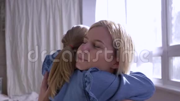 两个姐妹在房子的窗户附近拥抱并温柔地看着对方视频的预览图