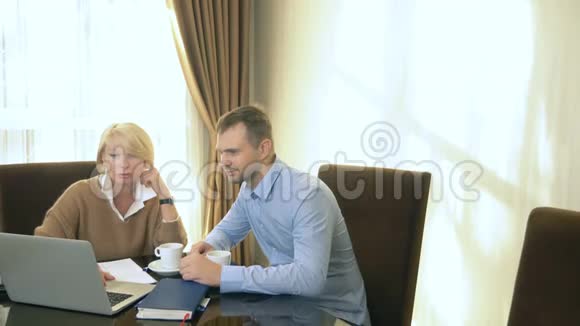 男人和女人坐在办公室手提电脑前说话视频的预览图