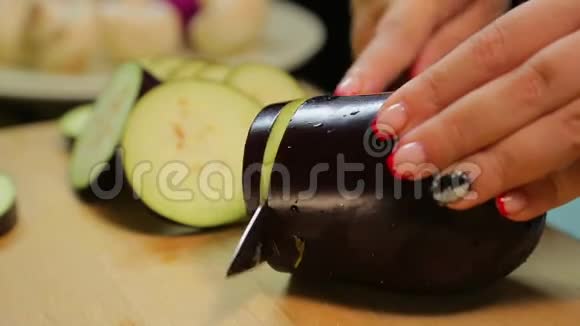 一个女人正在用一把刀在木板上切一个中等的茄子视频的预览图