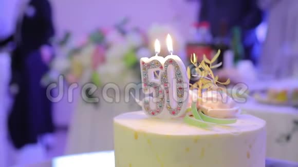 生日蛋糕和50年和两支蜡烛在蛋糕的背景上鼓掌视频的预览图