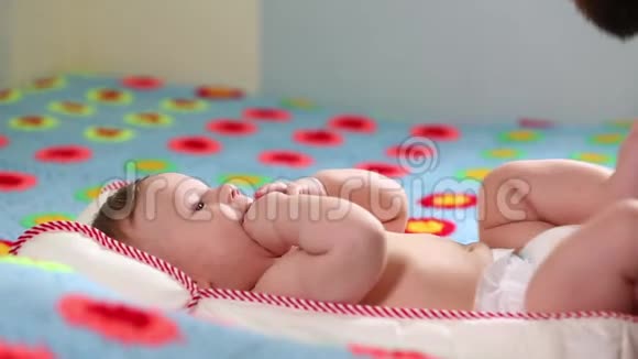 胡子父亲千禧一代和他新生的孩子躺在床上玩概念父子一个男人和一个新生儿视频的预览图