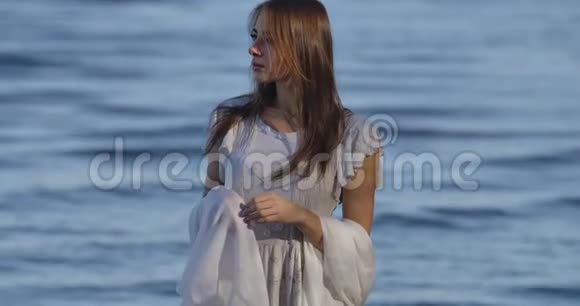 一位思想深邃的白种人女人站在海浪的背景上穿着浅白的裙子有魅力的女孩视频的预览图