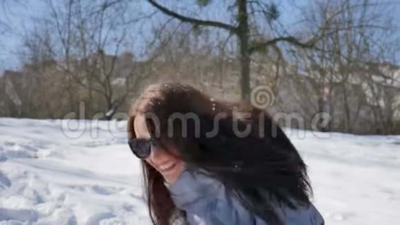 在公园里戴着黑色太阳镜和黑色直发的漂亮女人在户外玩雪球的画像视频的预览图