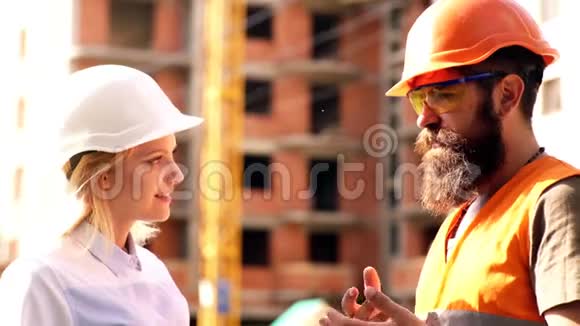 施工工人和工程师在施工现场交谈建筑区戴头盔的工人肖像视频的预览图