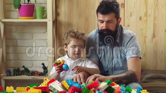 男人和男孩一起在木墙背景上玩耍家庭和童年的概念爸爸和孩子搭塑料积木视频的预览图