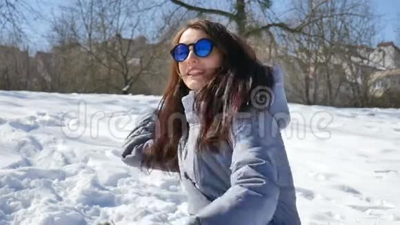 穿着蓝色镜子太阳镜和黑色直发的成年女孩在户外玩雪球真是太棒了视频的预览图