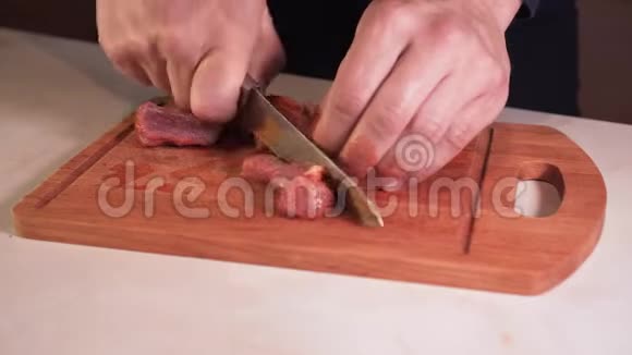 一个男人的手在切割板上切生肉特写镜头视频的预览图