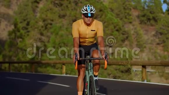 一个穿黄色T恤的男人骑着自行车骑在山蛇上视频的预览图