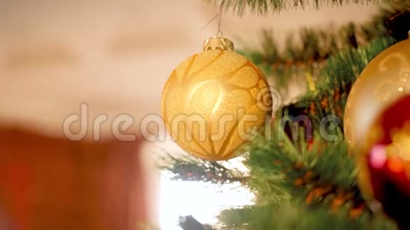 客厅圣诞树上悬挂和旋转的金色闪闪发光的宝珠特写4k视频视频的预览图