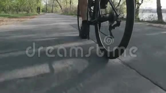 骑自行车的人骑着自行车跟着射击自行车轮旋转在城市公园里骑自行车慢动作视频的预览图