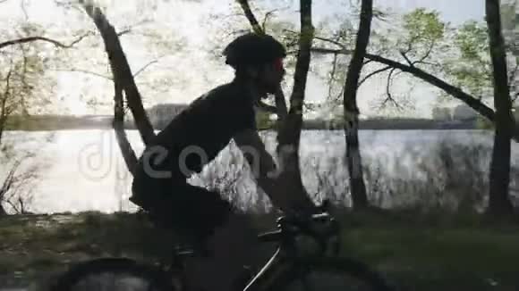 带胡子的年轻骑自行车的人穿着黑色的衣服喝水在沿河公园骑自行车轻松恢复视频的预览图