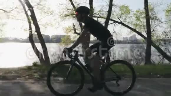 瘦小的三项运动员在自行车饮水阳光透过树木照耀训练期间口渴的三项运动员喝水三项全能视频的预览图