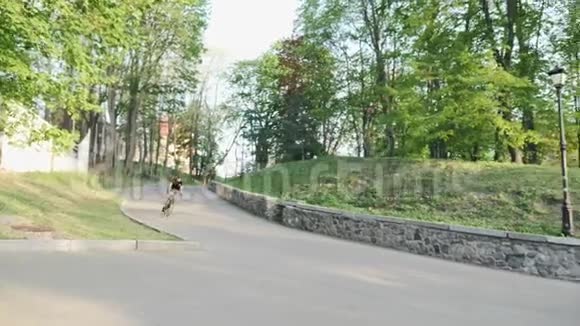 专业强壮的瘦自行车骑手在弯曲的道路上下降穿着黑色球衣和短裤从山上下来的线人视频的预览图