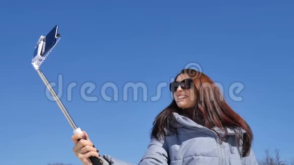 在晴朗的春天蓝天上美丽的女人戴着深色太阳镜在城市公园户外自拍视频的预览图