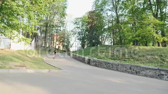 专业强壮的瘦自行车骑手在弯曲的道路上下降穿着黑色球衣和短裤从山上下来的线人慢慢视频的预览图