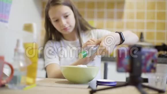在家厨房里做毛茸茸的黏液的少女视频的预览图
