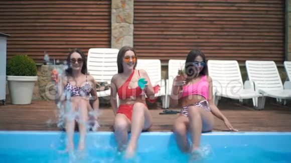 游泳池边有鸡尾酒的漂亮女孩女孩们泼水慢动作视频的预览图