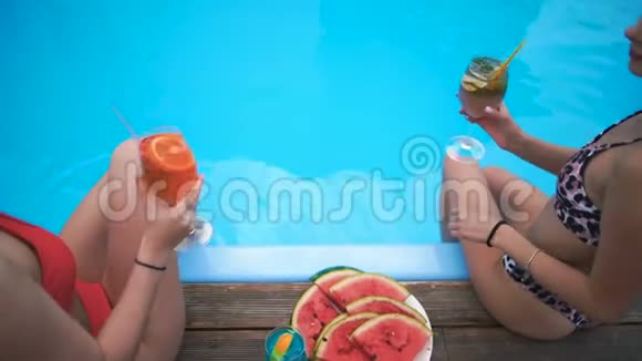 女孩们在度假胜地的游泳池里放松喝着鸡尾酒和水果慢动作视频的预览图