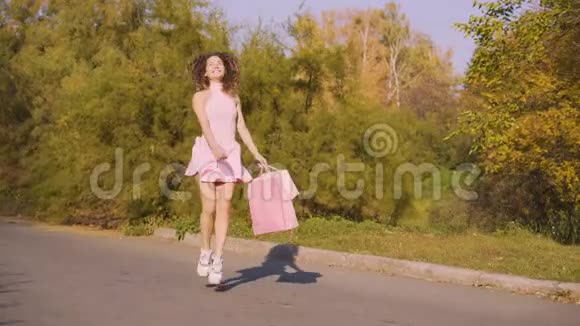 快乐女孩带着包裹在公园里散步女人手里拿着商场里的纸袋4K视频的预览图