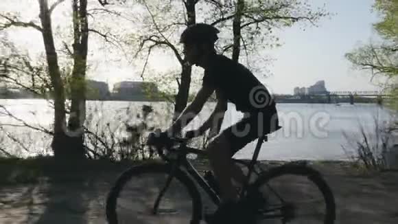 骑自行车时骑自行车的人从水瓶里喝水口渴的骑自行车的人骑在城市公园沿河视频的预览图