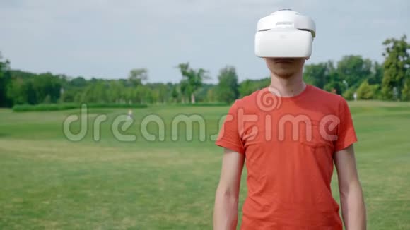 一个男人在公园里用VR耳机转右视频的预览图