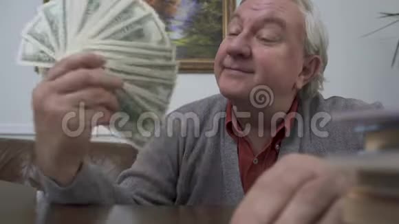 快乐的老人把钱凑近他的脸积极的富人展示了他的钱有趣的祖父视频的预览图