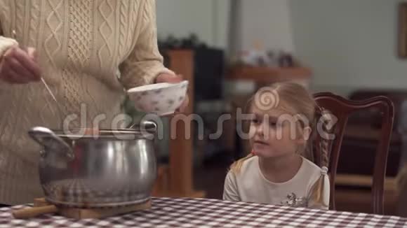 外婆坐着等着把罗宋汤倒在她可爱的小孙女的碗里视频的预览图