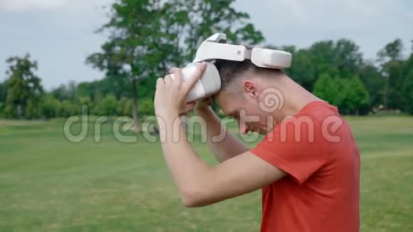 一个男人从公园的头上摘下他的VR耳机视频的预览图