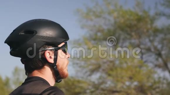骑自行车者训练前饮用水的背面肖像穿黑色服装头盔和太阳镜视频的预览图