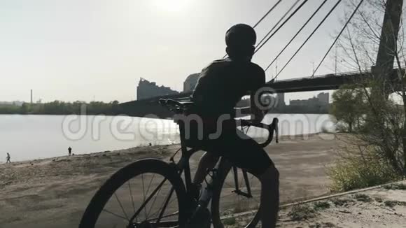 强壮健康的运动自行车手坐在自行车上看着前方梦想着未来桥和河的背景视频的预览图