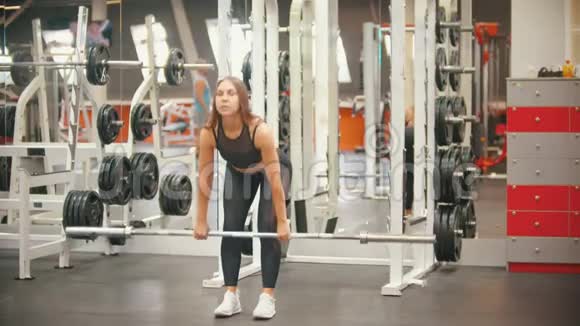 一位在健身房训练腿脚的运动员女子手里拿着一个铁哑铃身体向下倾视频的预览图
