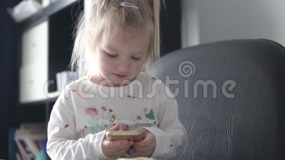 美丽的小女孩手里拿着手机看着屏幕视频的预览图