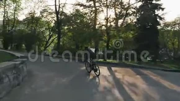骑自行车的人骑在公园路上骑着自行车下山的瘦小的骑车人视频的预览图