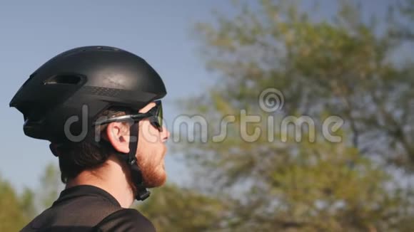 骑自行车者训练前饮用水的背面肖像穿黑色服装头盔和太阳镜慢动作视频的预览图