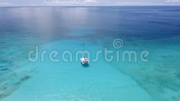 鸟瞰孤独豪华双体游艇在晶莹剔透的蓝色泻湖与反射光拉迪格岛视频的预览图
