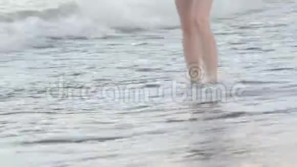 美丽的女性腿沿着冲浪线沿着干净的沙子行走日落时间视频的预览图