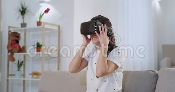 在沙发上的客厅里一个集中的漂亮女人用虚拟现实眼镜给她留下了深刻的印象视频的预览图