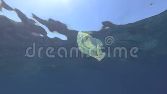 塑料污染蓝色水中黄色塑料袋慢动作丢弃的塑料袋慢慢地飘浮在蓝色的水面下视频的预览图