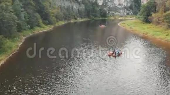 飞过河流河上漂浮着双体船漂流在一条带岩石的山河上视频的预览图