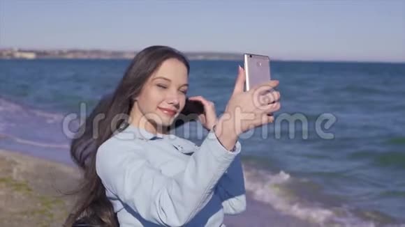 坐轮椅的年轻残疾妇女在海边的沙滩上玩得很开心用手机拍照自拍视频的预览图